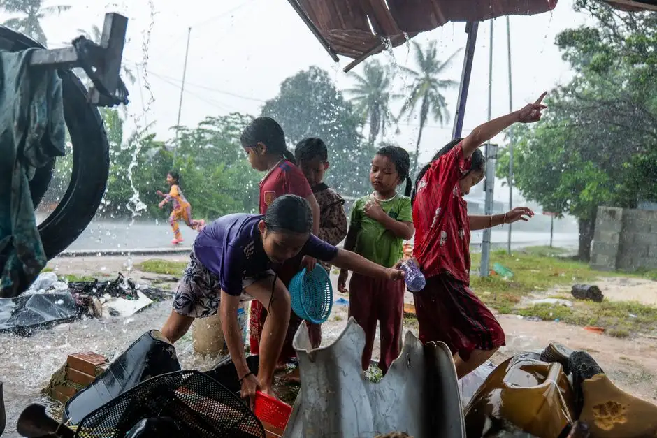 Children enjoying rain under a shelter, showcasing joy and playfulness on a rainy day.